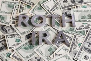 words ROTH IRA laid with aluminium letters on the US dollar banknotes background photo