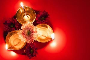 Happy Diwali. Traditional Hindu celebration. Diya oil lamps and flowers on red background. Religious holiday of light. photo