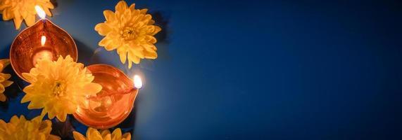 fiesta india de diwali. lámparas de aceite diya tradicionales y flores amarillas sobre fondo azul. celebrando el festival de la luz. foto