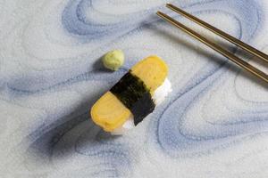 Japanese food tamagoyaki sushi on plate has chopsticks on background. photo