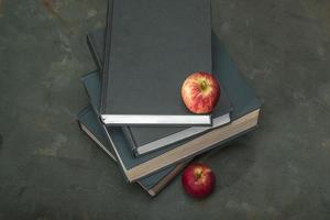 manzana en la pila de libros sobre el estudio de la mesa de madera verde. foto