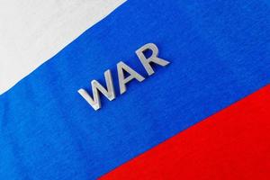 la palabra guerra puesta con letras de metal plateado en la bandera tricolor de la federación rusa foto