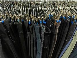 A row of hangers with cheap pants in the store in a market. Close-upw with selective focus. photo