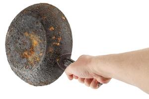 bare caucasian hand holding empty old cast iron frying pan photo