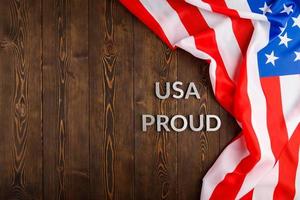 words USA proud laid with silver metal letters on brown wooden surface with flag of United States of America photo