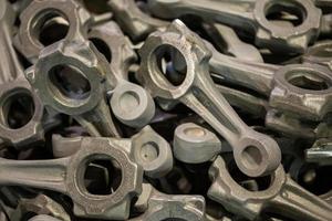 pile of crankshaft connecting rod forgings after cooling and shot blasting operations, close-up with selective focus photo