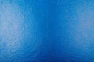 full frame flat background and texture of crumpled blue plastic film photo