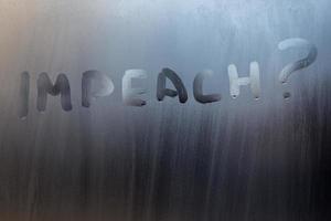 the question impeach written on wet window glass close-up with blurred background photo