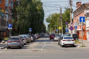 tula, rusia, 2 de agosto de 2021, abrumadoras señales de tráfico a lo largo de la estrecha calle de la ciudad de verano a la luz del día con muchos junto con autos estacionados. foto