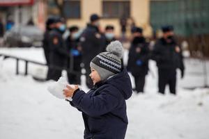 TULA, RUSSIA JANUARY 23, 2021 Public mass meeting in support of Navalny. Child playing snoball in front of blurry group of police officers. photo