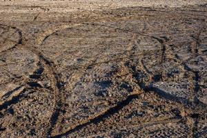 dry sand and mud ground with many dirt bike tracks at daylight photo