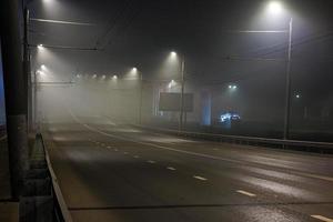 illuminated empty foggy night road with rigid guardrails photo