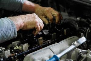 hands of caucasian mechanic unscrewing diesel engine parts of modern SUV photo