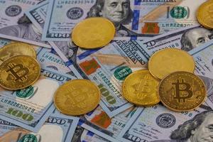 yellow bitcoin coins scattered over US dollar paper banknotes, closeup photo