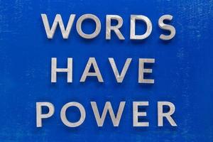 la frase las palabras tienen poder colocadas en un tablero pintado de azul con gruesos caracteres alfabéticos de metal plateado. foto