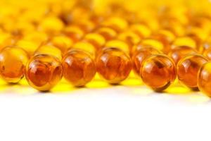 orange spherical ball capsules of fish oil selective focus isolated on white background photo