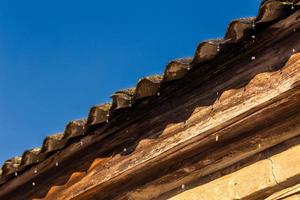 spring water drops flying from edge of an old barn roof photo