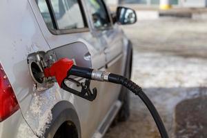 silver metallic car refueling on winter day gas station - close-up with selective focus and blurry background photo