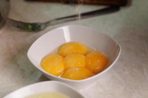salted five raw chicken egg yolks in a white ceramic bowl photo