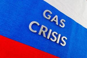 the words gas crisis laid with silver letters over flat russian flag surface photo