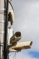 two old cctv security surveillance cameras on street light pole on blue sky background photo