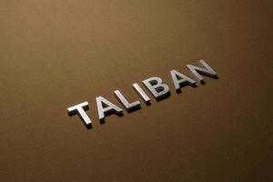 the word taliban laid with silver metal letters on rough tan khaki canvas fabric photo