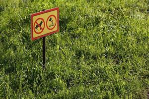 yellow sign with chemical application no dogs on green lawn background - close-up with selective focus photo