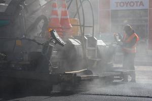 tula, rusia 16 de mayo de 2021 proceso de asfaltado, máquina pavimentadora de asfalto durante los trabajos de construcción de carreteras, en el día de verano foto