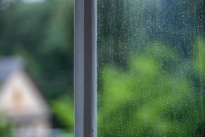 fondo abstracto de vidrio de ventana húmedo con gotas de agua de lluvia. fondo borroso verde de verano y enfoque selectivo y espacio de copia foto