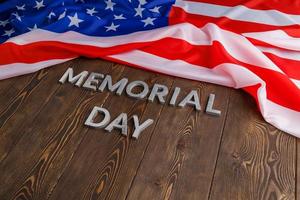 the words memorial day laid with silver metal letters on wooden board surface with crumpled usa flag photo