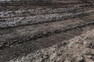 close-up full frame view of wet muddy dirt road at evening sun light photo