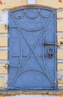 Old forged iron door with rivets and peeling blue paint photo