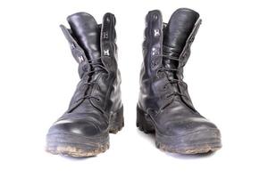 botas negras militares sucias y polvorientas usadas aisladas en la espalda blanca foto