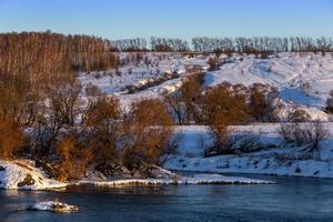 amateur winter riverside landscape with birch forest and slope photo