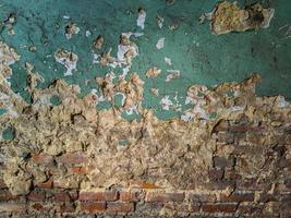 heavy damaged green painted plaster and bricks wall background and texture photo