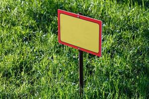 blank yellow sign mockup on green lawn background - close-up with selective focus photo