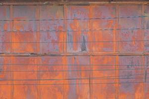 full frame background and texture of rusted steel sheet wall and horiozntal wires in front of it photo