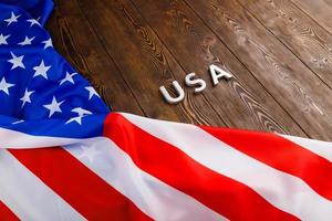 the word USA laid with silver metal letters on wooden board surface with crumpled flag of United States of America photo