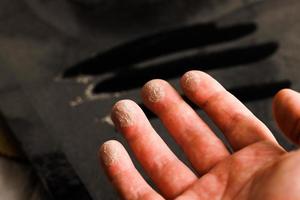 caucasian hand with dust on finger tips after touching black dusty surface photo