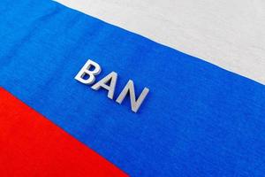 the word ban laid with silver metal letters over fabric Russian Federation flag photo