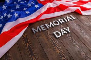 the words memorial day laid with silver metal letters on wooden board surface with crumpled usa flag photo