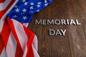 the words memorial day laid with silver metal letters on wooden board surface with crumpled usa flag photo