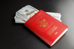 russian international passport with inserted US dollars on black background photo