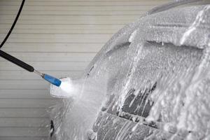 soap detergent foam application process while washing indoors at self-service carwash station photo