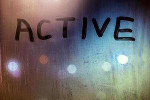 the word active written on night wet window glass close-up with bokeh background photo