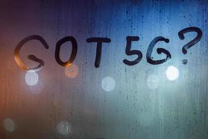 the question got 5G written by finger on wet glass with blurred lights in background photo