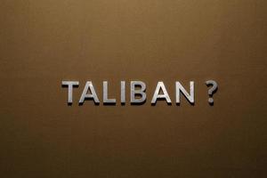 the question taliban laid with silver metal letters on rough tan khaki canvas fabric photo