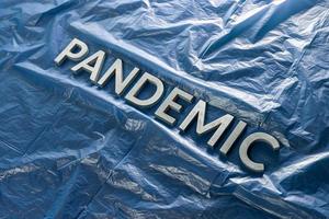 the word pandemic laid with silver letters on crumpled blue plastic film - diagonal perspective composition with selective focus photo