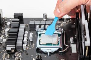 hand applies gray thermal grease on central processor unit in pc motherboard photo