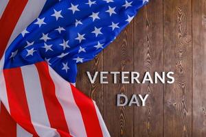 the words veterans day laid with silver metal letters on wooden board surface with crumpled usa flag photo